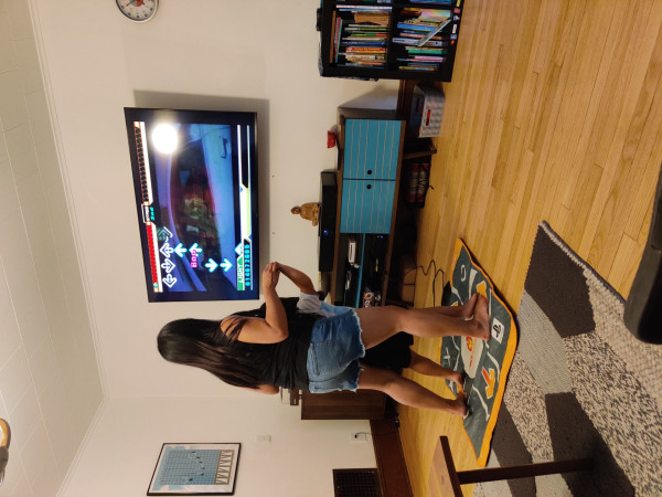 A mother playing Dance Dance Revolution with her daughter on the same dance pad.