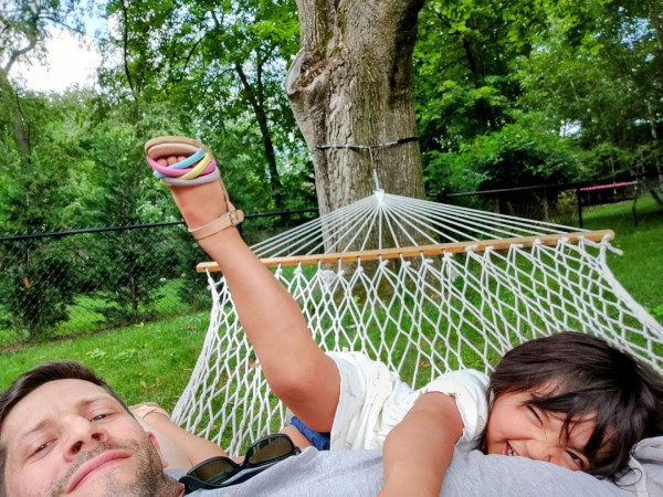 Selfie: photographer in hammock with daughter, who is trying to reposition herself for the photo. Her right leg is sticking straight in the air, precariously above the photographer's face.
