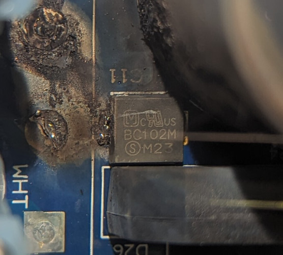 A chip on a PCB, scorched.
M with inward curled legs encased within a squarical, small 'c', a unidentified logo, "US"
"BC1O2M"
Circled 'S', "M23"